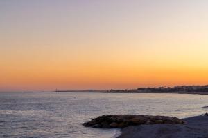 una roccia nell'acqua con un tramonto sullo sfondo di Crisol Promenade a Nizza
