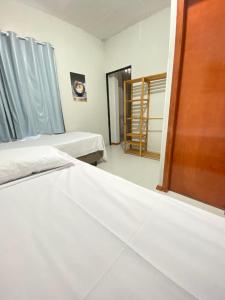 a bedroom with two beds and a window and a door at Pousada Âncora in Gravataí +33 photos