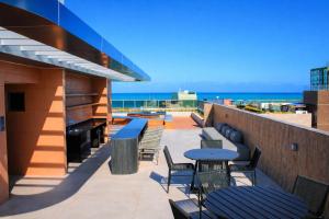 een patio met tafels en stoelen en de oceaan bij W Tambaú Apart Hotel in João Pessoa