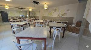 a restaurant with wooden tables and white chairs at Olas del Mar Hotel by GHO Hoteles in Santa Marta +31 photos