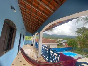 a hammock on the balcony of a house with a swimming pool at Espaço Sol in Peruíbe