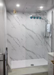een badkamer met douche en witte marmeren muren bij Vacant Nests Ivy Cottage 3BR Wi-Fi in Banton