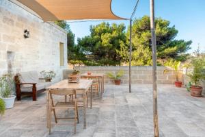 un patio con tavoli, sedie e un ombrellone di Antico Casolare P. P. a Otranto