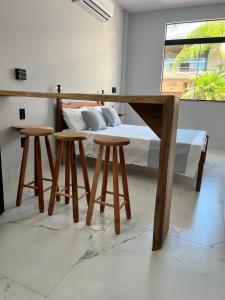 a bedroom with a bed and two stools at Pé na Areia in Guarapari