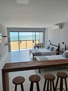 a bedroom with two beds and stools and a view of the beach at Pé na Areia in Guarapari