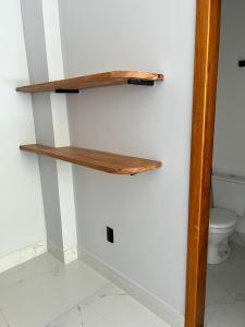 a bathroom with a wooden shelf on the wall at Pé na Areia in Guarapari +38 photos