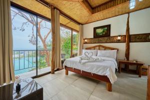een slaapkamer met een bed en een groot raam bij El Nido Viewdeck Cottages in El Nido