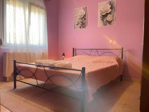 a bedroom with a bed with pink walls and a window at Villa Dreamy View in Agia Ermioni