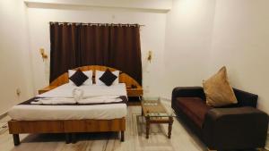a bedroom with a bed and a chair and a couch at Hotel Laxmi Palace Near ISBT Dehradun in Dehradun +1 photo
