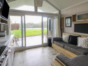 a living room with a couch and a sliding glass door at The Family Pod - Gower in Swansea