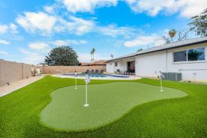 a yard putting green with two golf clubs on it at Private Pool Haven Backyard & Putting Green in Phoenix