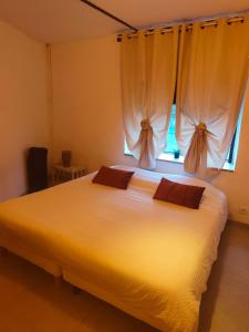 ein Schlafzimmer mit einem großen weißen Bett mit einem Fenster in der Unterkunft Appartement Terrasse à Mennetou sur Cher "La Cité Médiéval in Mennetou-sur-Cher