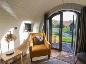 a living room with a chair and an open door at Glamping Pod 9 - Gower in Swansea