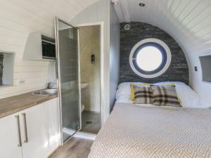 a small bedroom with a bed and a round window at Glamping Pod 9 - Gower in Swansea