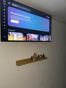 Ein Fernseher hängt an der Wand, daneben stehen Häuser auf einem Regal. in der Unterkunft MR Tiny House - Private Parking in Roşu