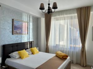 a bedroom with a bed with yellow pillows and a window at Summerlad Mamaia Beach in Mamaia