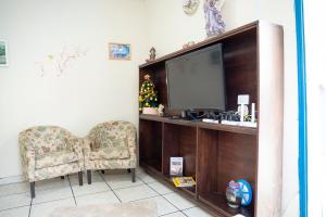 ein Wohnzimmer mit Fernseher und Sessel in der Unterkunft Casa Pet Friendly c 3 Quartos e Garagem no Jardim in Poços de Caldas