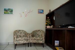 ein Wohnzimmer mit Sessel und Fernseher in der Unterkunft Casa Pet Friendly c 3 Quartos e Garagem no Jardim in Poços de Caldas