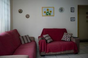 ein Wohnzimmer mit einem roten Stuhl und einem Sofa in der Unterkunft Casa Pet Friendly c 3 Quartos e Garagem no Jardim in Poços de Caldas + 26 Fotos