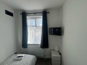 une chambre avec un lit et une fenêtre avec des rideaux bleus dans l'établissement BXH B4 Cozy single room Bexleyheath, à Bexleyheath
