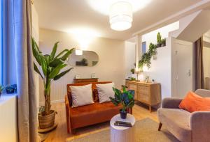 een woonkamer met een bank en een stoel bij Le Botanique - 15 min Paris et Stade de France - 50m2 - 2 chambres in Aubervilliers