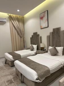 una camera d'albergo con due letti e una finestra di شاليهات روز a Al Shafa