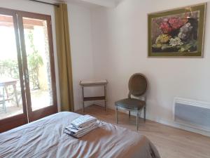 een slaapkamer met een bed en een stoel en een schilderij bij La Bouriotte in Labastide-Rouairoux