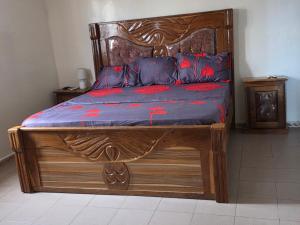 a wooden bed with a wooden frame with red flowers on it at Villa duchesse in Sali Nianiaral