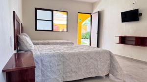 een slaapkamer met een bed en een tv aan de muur bij Hotel Villa Chucum in Tikuch