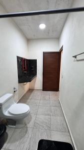 een badkamer met een toilet en een houten deur bij Hotel Villa Chucum in Tikuch