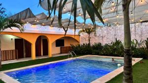 een zwembad voor een huis met een palmboom bij Hotel Villa Chucum in Tikuch