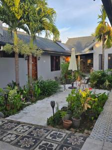 ein Innenhof mit einer Terrasse, Palmen und einem Sonnenschirm in der Unterkunft Bula Lodge Guest House in Nadi