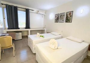 una camera d'albergo con due letti e un tavolo di Manacá Hotel a Foz do Iguaçu