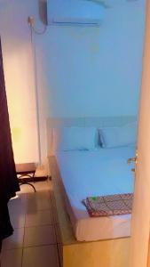 een wit bed in een kamer met een blauw licht bij Villa Romaine in Toubab Dialaw