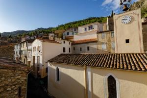 eine Gruppe von Gebäuden mit einem Uhrturm in einer Stadt in der Unterkunft Ostal de la placette in Padern