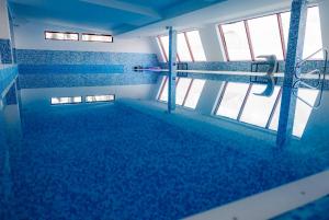 a large swimming pool with blue tile floors and windows at Springview Studio in Bucharest