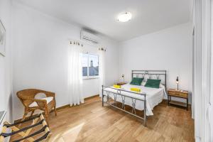 ein weißes Schlafzimmer mit einem Bett und einem Stuhl in der Unterkunft Villa Casa Alice by Villa Plus in Carvoeiro + 11 Fotos