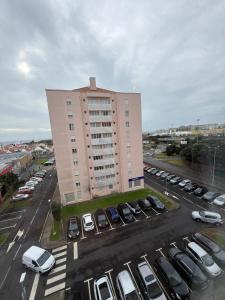 een groot gebouw met auto's geparkeerd op een parkeerplaats bij City center Loreto in Ponta Delgada