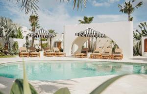 ein Pool mit Liegestühlen und Sonnenschirmen neben einem Gebäude in der Unterkunft Dolce One-Bedroom Villas in Uluwatu + 19 Fotos
