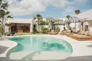 ein Swimmingpool in einem Hof mit Liegestühlen und einem Haus in der Unterkunft Dolce One-Bedroom Villas in Uluwatu