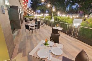 ein Restaurant mit Tischen und Stühlen auf einer Terrasse in der Nacht in der Unterkunft Sonesta Hotel Cali in Cali