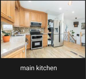 a kitchen with wooden cabinets and a stainless steel refrigerator at Private Bed Room in a Beautiful Family House in Brossard