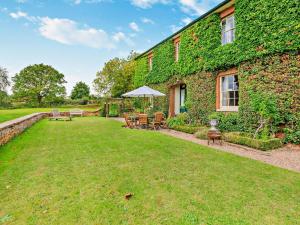 een tuin met stoelen en een parasol naast een gebouw bij 5 Bed in Fitzhead 95570 in Fitzhead