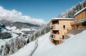 un edificio sul fianco di una montagna innevata di Lahnerhof Chalets a Lutago