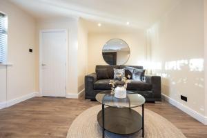 een woonkamer met een bank en een glazen tafel bij Calgary Residence in Mellor