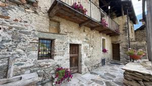 a stone building with a door and flowers on it at Mansio 1695 Chambres d'hôtes in Pont-Saint-Martin