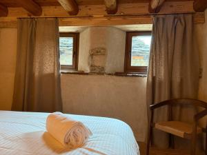 a bedroom with a bed and a chair and two windows at Mansio 1695 Chambres d'hôtes in Pont-Saint-Martin