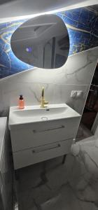 een badkamer met een witte wastafel en een spiegel bij Cozy Loft sous les toits in Le Kremlin-Bicêtre