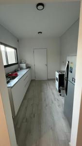 Il comprend une cuisine avec des murs blancs et du parquet. dans l'établissement Dúplex con Garage Esperanza, à Esperanza