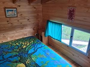 埃博森Sur tiny house的小木屋内一间卧室,配有一张床和一个窗户